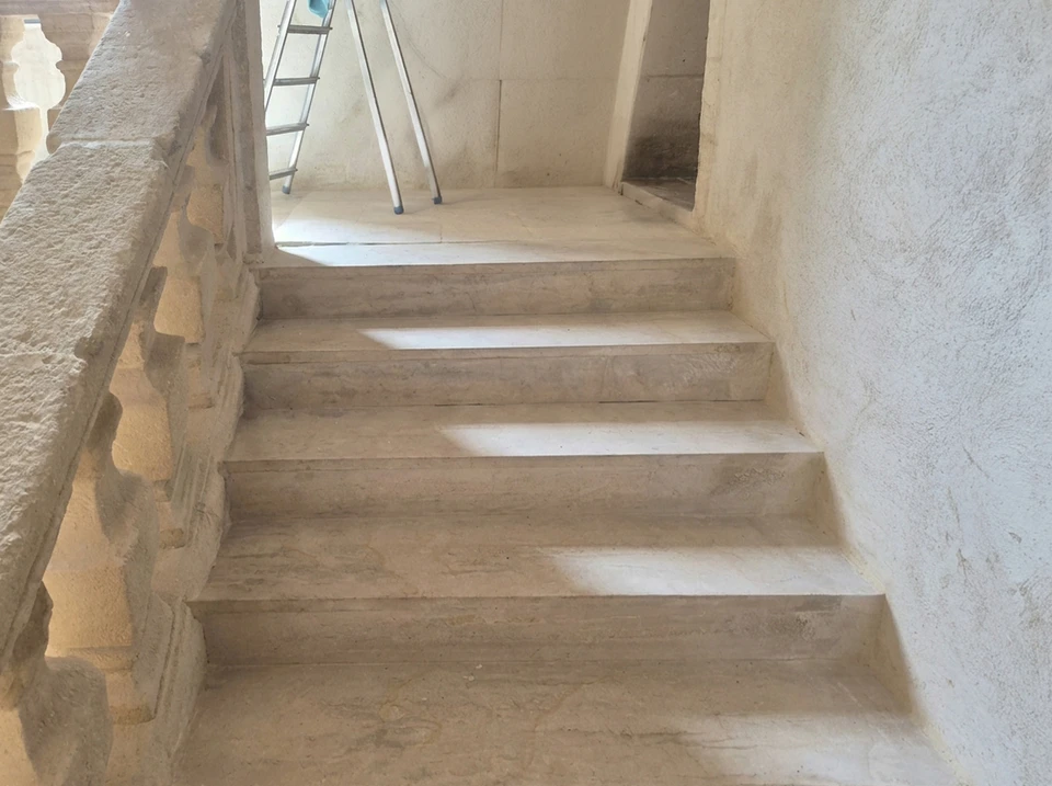 Chantier extérieur en cours, vue latérale d'un bâtiment neuf avec façade enduite blanche et menuiseries PVC blanches